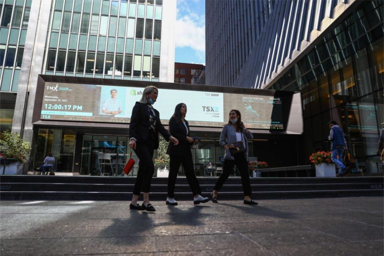 A sign board displays the TSX as women walk past the Richmond Adelaide Centre in the financial district in Toronto on Sept. 29, 2021.